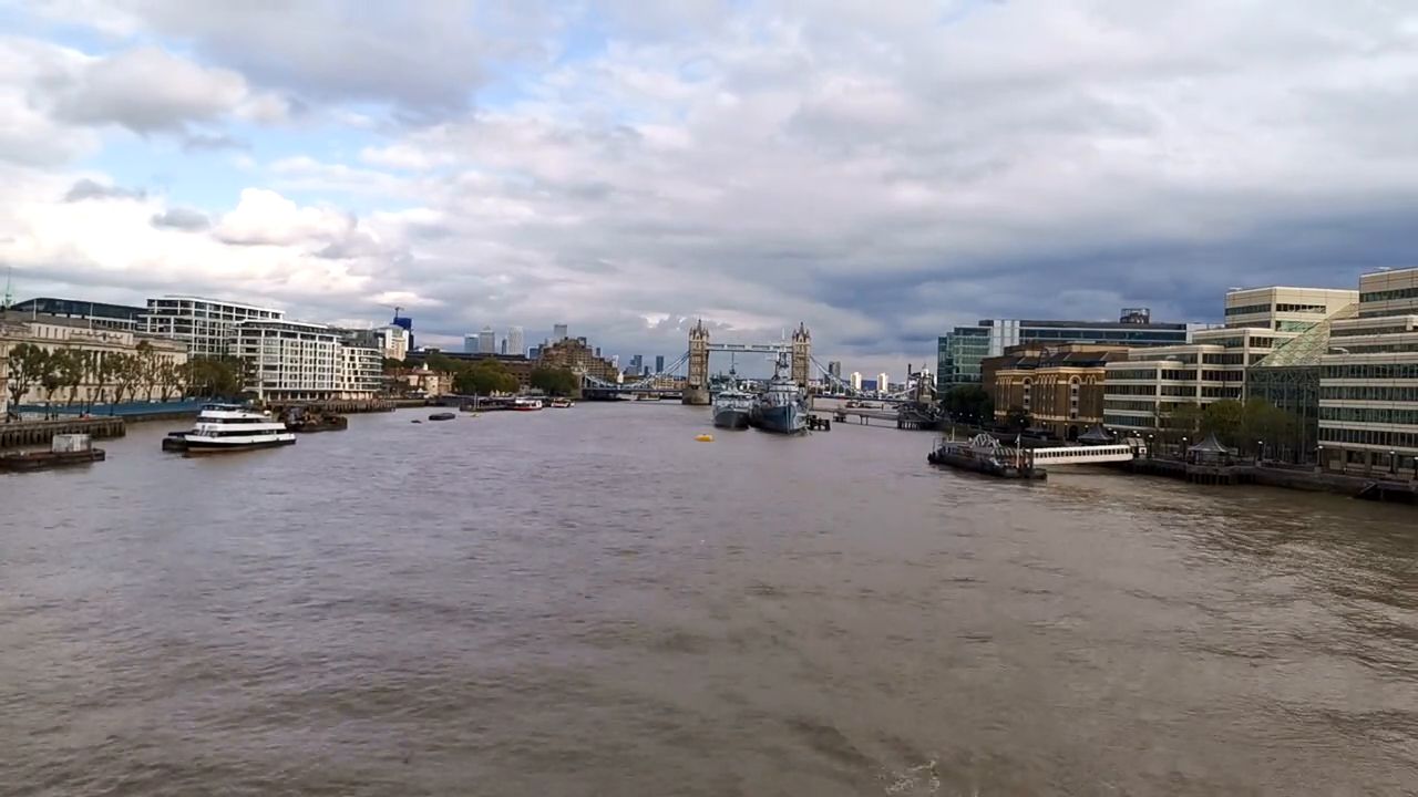 A wide view down the Thames on a cloudy day, with Tower Bridge small in the distance