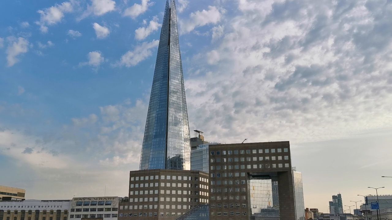 The Shard, a tall glass spire, against a blue sky with white clouds